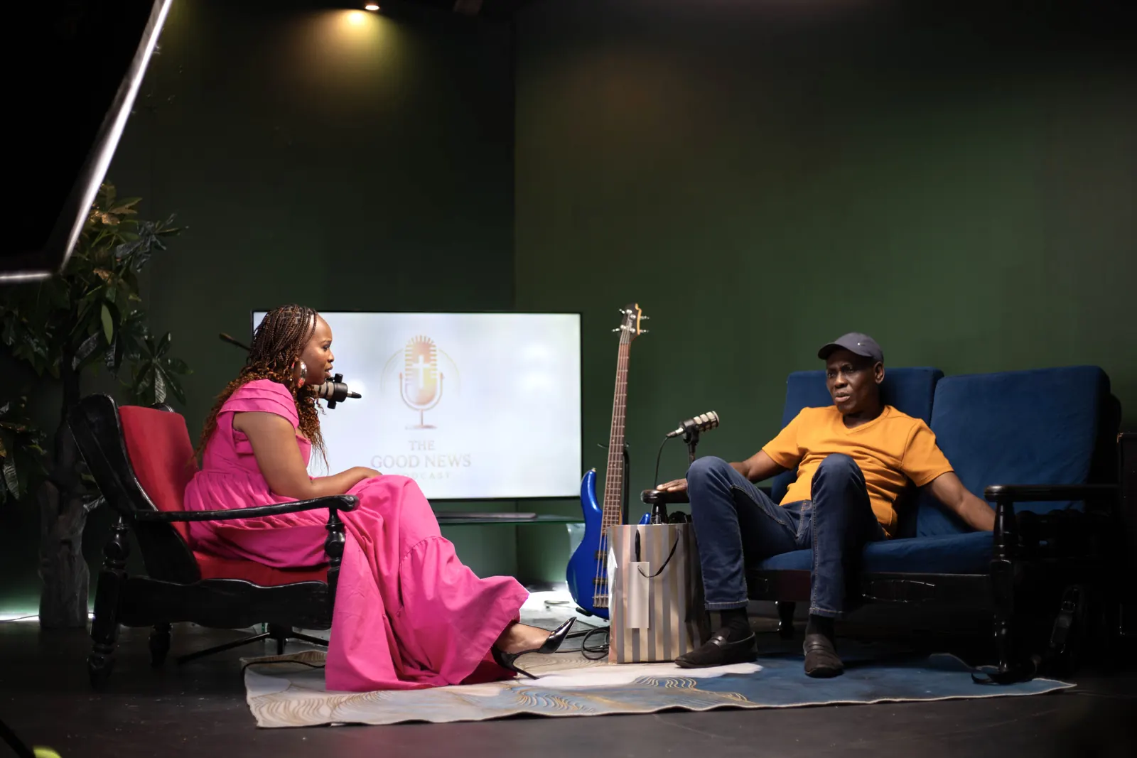 Host and guest recording a ministry podcast on the SN7 set, with a screen and a bass guitar behind them.