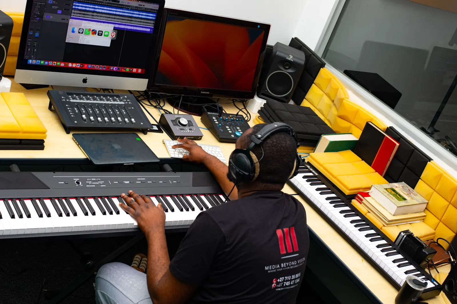 Engineer at the SN7 control room desk with studio monitors, a keyboard, and a session on screen.